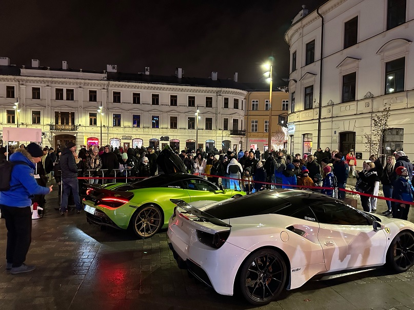 McLaren i Ferrari podczas nocnego pikniku charytatywnego Fundacji FunAndDrive Dzieciom na rynku miejskim - tłum widzów wokół aut