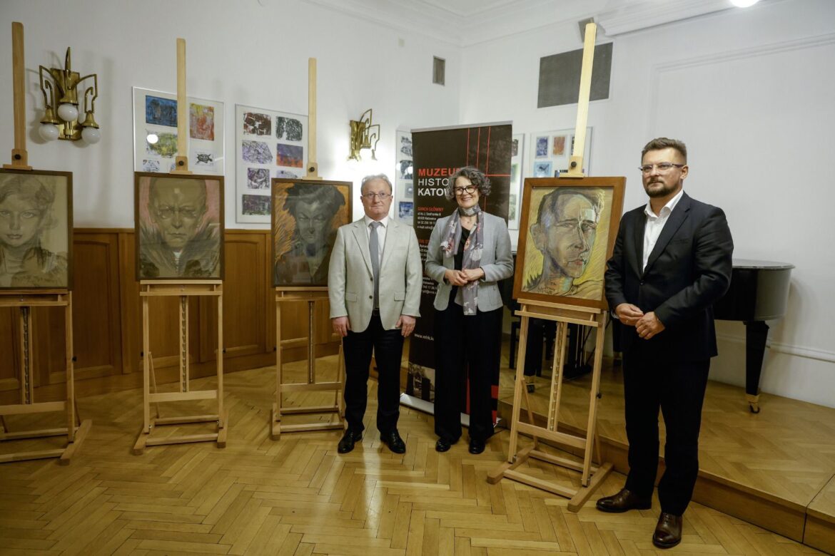 Trzy osoby stoją wśród sztalug z pastelowymi portretami Witkacego w sali Muzeum Historii Katowic. Na ścianie w tle widoczne dodatkowe prace z kolekcji artysty.