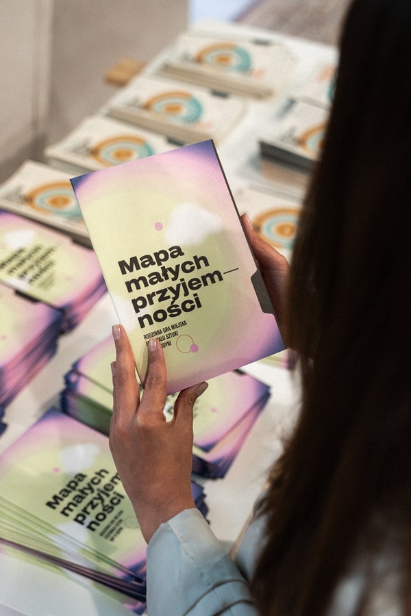 Uczestniczka festiwalu Sny o Gdyni trzyma broszurę gry miejskiej Mapa małych przyjemności